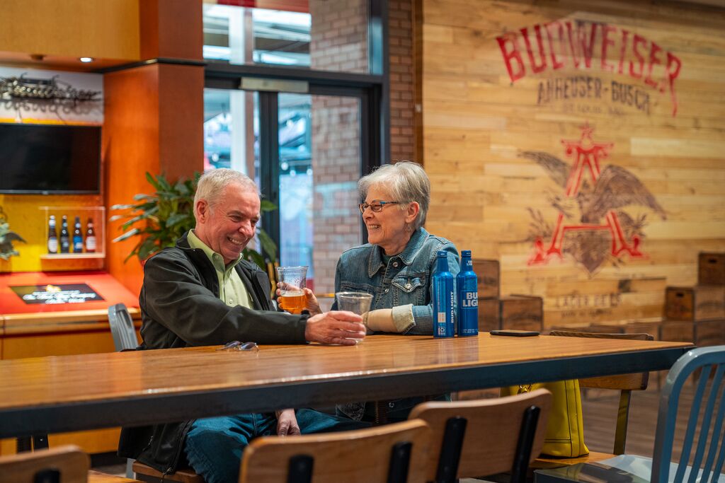 A couple sit at a bar table and talk while enjoying fresh brewed beer.