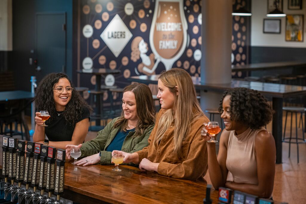 Four people sit at a bar and drink different styles of craft beer. 